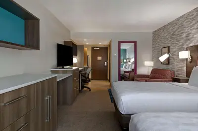 a hotel room with two beds and a flat screen tv at Home2 Suites By Hilton Barstow, Ca in Barstow