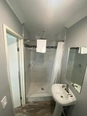 a white bathroom with a shower and a sink at La Perla motel in South Gate