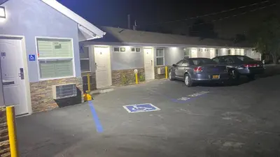 two cars parked in a parking lot in front of a house at La Perla motel in South Gate