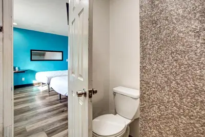 a bathroom with a toilet and a bedroom with blue walls at High Desert Inn in Hesperia