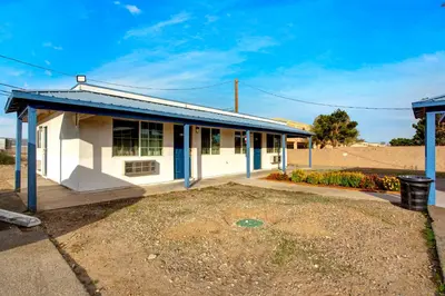 a small white building with a blue roof at High Desert Inn in Hesperia