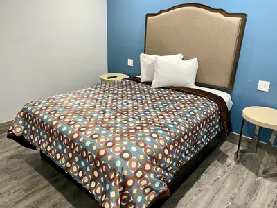 a bedroom with a large bed with a colorful comforter at Dixie Motel in Compton