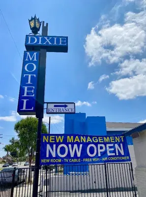 a sign for a new management now open at Dixie Motel in Compton