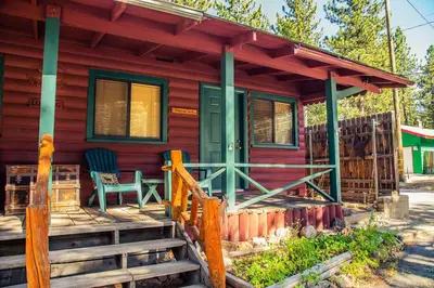 a red house with a green door and two chairs on a porch at Eagle's Nest in Big Bear Lake
