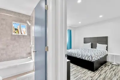 a bedroom with a bed and a bath tub next to a bathroom at Tradewinds Motel in Lakewood