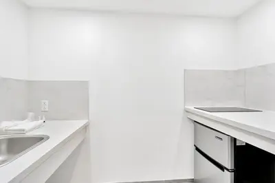 a white kitchen with a sink and a counter at Tradewinds Motel in Lakewood