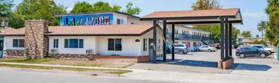 a building with a bus stop in a parking lot at Tradewinds Motel in Lakewood