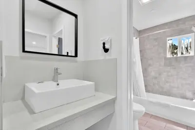 a white bathroom with a sink and a mirror at Tradewinds Motel in Lakewood