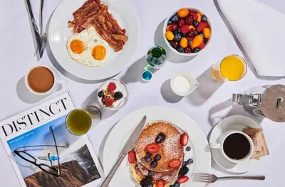 a table topped with plates of breakfast foods and coffee at The Sun Rose West Hollywood in Los Angeles