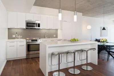 a kitchen with white cabinets and a counter with bar stools at AKA West Hollywood in Los Angeles