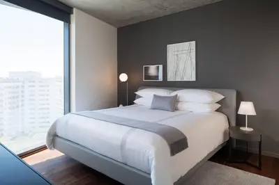 a bedroom with a large bed and a large window at AKA West Hollywood in Los Angeles