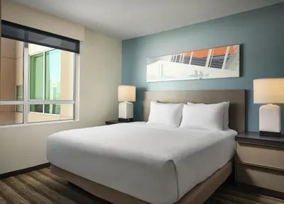 a bedroom with a large bed and two windows at Hyatt House LA - University Medical Center in Los Angeles