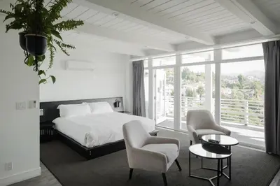 a bedroom with a bed and chairs and a large window at Hollywood Hills Hotel in Los Angeles