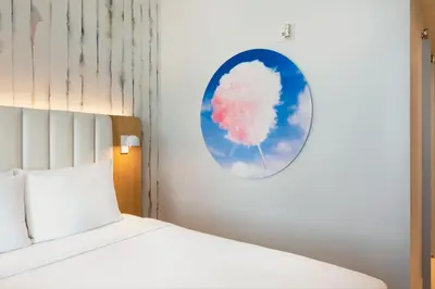 a bedroom with a bed and a cloud painting on the wall at The Viv Hotel, Anaheim, a Tribute Portfolio Hotel in Anaheim