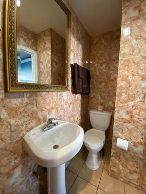 a bathroom with a sink and a toilet and a mirror at Sands Inn in South Gate