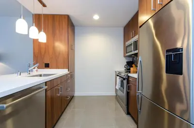 a kitchen with wooden cabinets and a stainless steel refrigerator at Cityscape Luxury High-Rise 1-Bedroom in Los Angeles