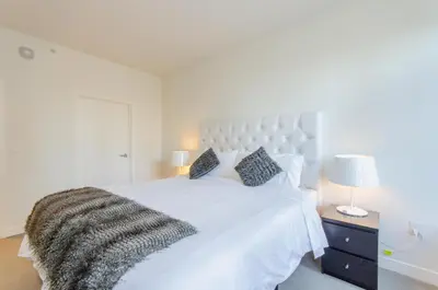 a white bedroom with a large white bed with a blanket at Cityscape Luxury High-Rise 1-Bedroom in Los Angeles