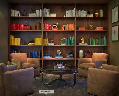 a living room with two chairs and a table and book shelves at Cityscape Luxury High-Rise 1-Bedroom in Los Angeles