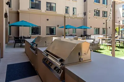 an outdoor kitchen with a grill and tables with umbrellas at SpringHill Suites by Marriott Valencia in Valencia