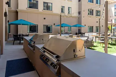 an outdoor kitchen with a grill and tables with umbrellas at Residence Inn by Marriott Valencia in Valencia