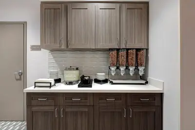 a kitchen with brown cabinets and white counter tops at Homewood Suites By Hilton Santa Clarita/Valencia, Ca in Santa Clarita