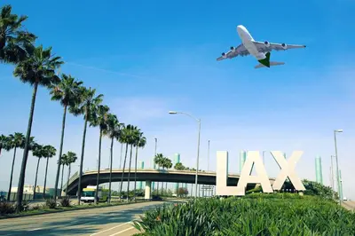 an airplane is flying over the lax sign with palm trees at Arlo Motel near LAX, SoFi Stadium in Inglewood
