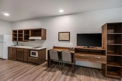 a kitchen with a desk with a tv and a counter at WoodSpring Suites Bakersfield Airport in Bakersfield