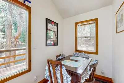 a dining room with a table and two windows at Babbling Brook in Lake Arrowhead