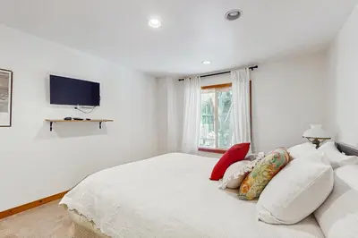 a white bedroom with a bed and a tv at Babbling Brook in Lake Arrowhead