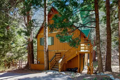 a tree house in the woods with a staircase at Babbling Brook in Lake Arrowhead