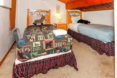a bedroom with two beds and a dog on the bed at Mountain Adventure - 1931 by Big Bear Vacations in Big Bear Lake