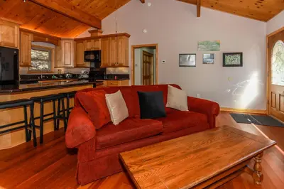 a living room with a red couch and a kitchen at Shasta Mountain Cabin - 1916 by Big Bear Vacations in Big Bear City
