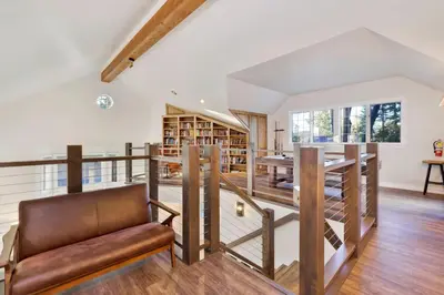 a living room with a staircase and a chair at Splash Mountain - 1904 by Big Bear Vacations in Big Bear Lake