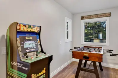 a game room with a pinball machine and a table at Splash Mountain - 1904 by Big Bear Vacations in Big Bear Lake