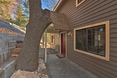a house with a tree next to a door at Mountainside Cabin with Deck - 16 Miles to Skiing! in Lake Arrowhead