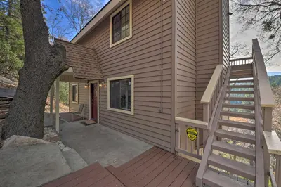 a house with a staircase next to a tree at Mountainside Cabin with Deck - 16 Miles to Skiing! in Lake Arrowhead