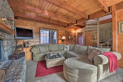 a living room with a couch and a fireplace at Mountainside Cabin with Deck - 16 Miles to Skiing! in Lake Arrowhead