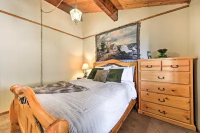 a bedroom with a bed with a dresser and a painting at Lake Arrowhead Cabin with Deck and Stunning Mtn Views! in San Bernardino