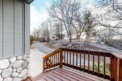 a wooden porch of a house with a stone wall at The House Of Light and Sky in Lake Arrowhead