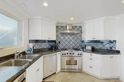a kitchen with white cabinets and a sink and a stove at Savor the View in Oxnard