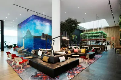 a lobby with couches and tables and a mural at citizenM Los Angeles Downtown in Los Angeles