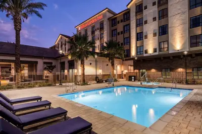 a hotel with a large swimming pool and palm trees at Hilton Garden Inn Chino Hills Pomona CA in Pomona