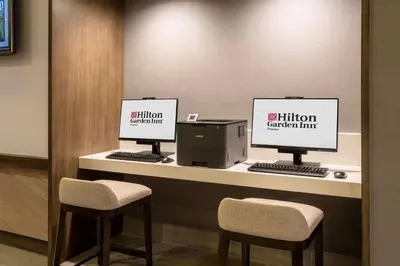 two computer monitors sitting on a counter with two chairs at Hilton Garden Inn Chino Hills Pomona CA in Pomona