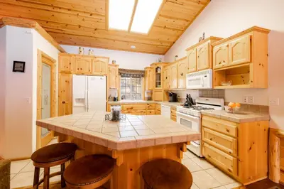 a kitchen with wooden cabinets and a island with stools at Little Cubs Cabin #1986 by Big Bear Vacations in Big Bear Lake