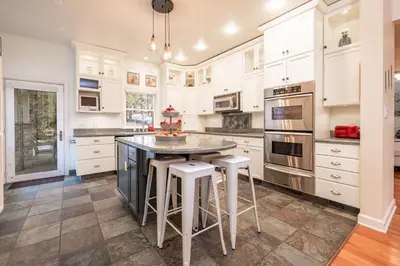 a kitchen with white cabinets and a island with stools at The Grand Chalet #1989 by Big Bear Vacations in Big Bear Lake