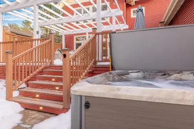 a hot tub in a backyard with a deck and stairs at The Grand Chalet #1989 by Big Bear Vacations in Big Bear Lake