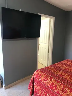 a bedroom with a bed and a flat screen tv on a wall at The Fly Inn Motel in Lynwood