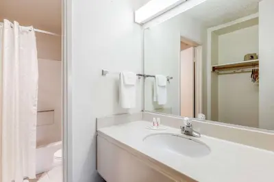 a white bathroom with a sink and a mirror at Super 8 by Wyndham Bakersfield/Central in Bakersfield
