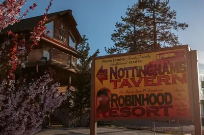 a sign in front of a house with a building at Robinhood Resort in Big Bear Lake
