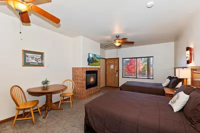 a bedroom with a bed and a table and a fireplace at Robinhood Resort in Big Bear Lake